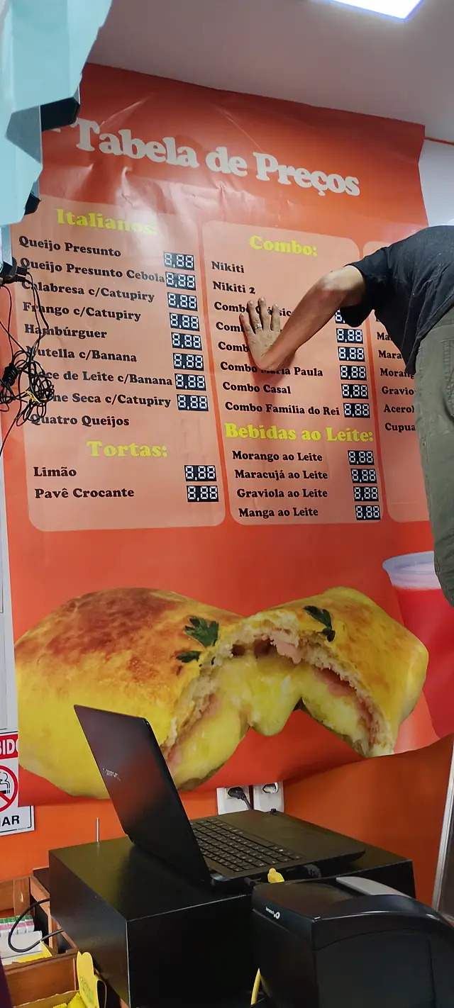 Aplicador posicionando a tabela de preços na parede